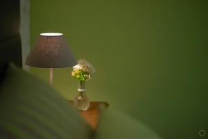 a lamp and a vase with flowers on a table at La Pastorale in Manhay