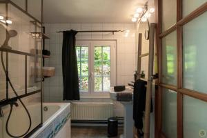 a bathroom with a tub and a sink and a window at La Pastorale in Manhay