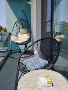 a balcony with two chairs and a table with a book at DML Apartment in Mamaia Nord