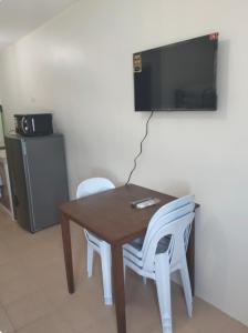 LagunaにあるRics Remarkable and Radiant Home in Dumaguete City - Marina Spatial B842の白い椅子2脚付きテーブル、壁掛けテレビ付