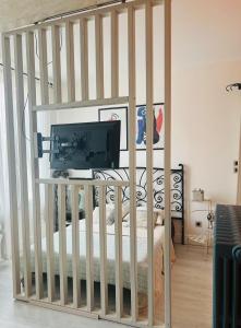 una camera da letto con una culla e una televisione sopra di Le nid des Petits à 15 min de Bordeaux a Sainte-Eulalie