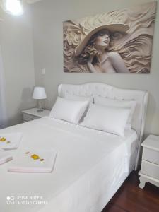 a bedroom with a white bed with a painting on the wall at Hospedagem Altas da Quitéria Suíte 02 in Catas Altas +7 photos