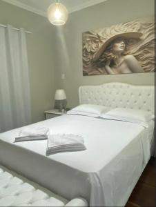 a white bed in a bedroom with a painting on the wall at Hospedagem Altas da Quitéria Suíte 02 in Catas Altas