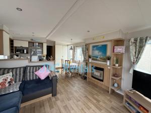 a living room with a blue couch and a kitchen at Golden Sands & Winkups in Kinmel Bay