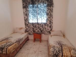 ein kleines Zimmer mit zwei Betten und einem Fenster in der Unterkunft Appart à Martil in Martil