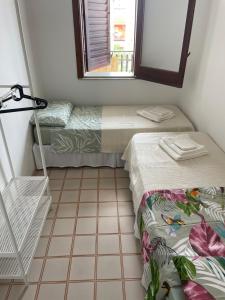 two beds in a room with a window and a tiled floor at Casa DeA in Giardini Naxos