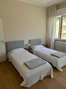 Dos camas en una habitación con paredes blancas. en Casa di Luka, en Misano Adriatico