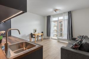a kitchen and living room with a sink and a couch at Fast-WiFi - Remote-Ready -15 min Airport - Balcony in Jūrmala