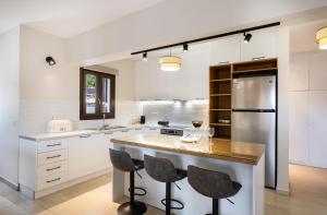 a kitchen with white cabinets and a island with bar stools at G&S House in Tsoukalades