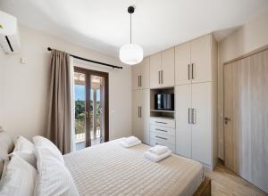 a white bedroom with a bed and a window at G&S House in Tsoukalades