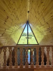 a window in a wooden ceiling with a view of a park at Rancho Didostati in Dzveli Abasha