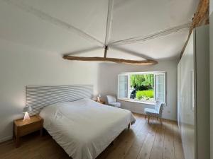 a bedroom with a bed and two chairs and a window at Maison Zen 2 chambres - Touverac in Touvérac