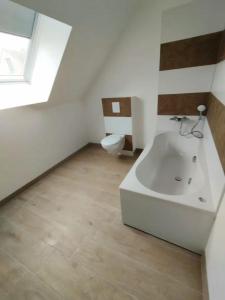 a bathroom with a white tub and a toilet at La Grange - Maison et Parking - Portes de Chartres in Jouy