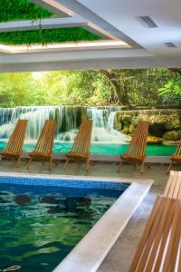a pool with chairs and a waterfall in the background at Panorama Tornik Zlatibor P4 apartman in Zlatibor