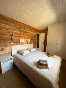 a bedroom with a large white bed with wooden walls at La Maison de la forêt et son jaccuzy in Biscarrosse +24 photos