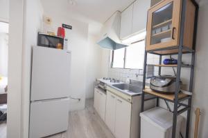 eine kleine Küche mit einem weißen Kühlschrank und einer Spüle in der Unterkunft shan-Nishiochiai 2F in Tokio