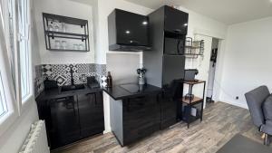 a kitchen with black cabinets and a desk at Escapade à 2 pas de la Loire in Sandillon