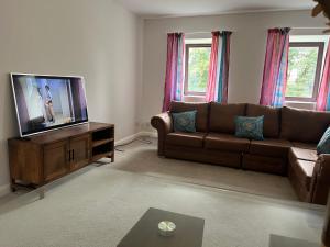 a living room with a couch and a flat screen tv at Stay Still Indian Court in Dalston