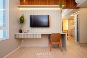 a room with a desk with a television on a wall at Studios aconchegantes no Setor Marista BLS in Goiânia +164 photos