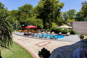 eine Terrasse mit Stühlen und Tischen und ein Pool in der Unterkunft Hlidi Hotel in Kókkinon Nerón