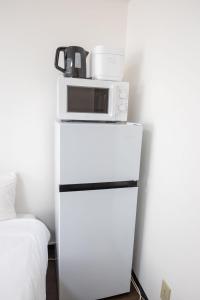 a microwave sitting on top of a white refrigerator at Palasto Hostel in Tokyo