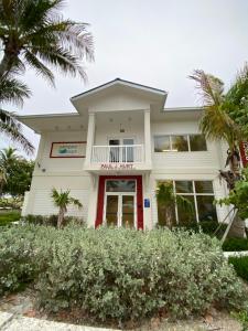 a white house with palm trees in front of it at Maison à Pompano Beach près de la mer in Pompano Beach