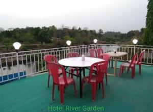 a group of tables and chairs on a balcony at Hotel River Garden Jambhulpada in Jambhulpāda +1 photo