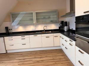 a kitchen with white cabinets and stainless steel appliances at Ferienwohnung Weseker Auszeit in Borken