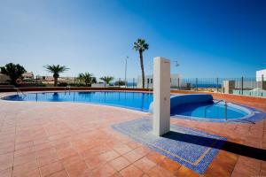 una piscina con una palmera al fondo en Holiday relax apartment, en Adeje