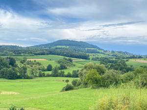 Un campo verde con árboles y montañas al fondo. en 3-Zimmer-FeWo Hexenhäusle Bollschweil, en Bollschweil