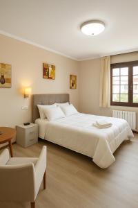 una camera da letto con un grande letto bianco e una sedia di Elara MSuites a Viveiro