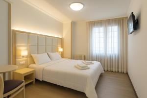 una camera d'albergo con un letto bianco e una finestra di Elara MSuites a Viveiro