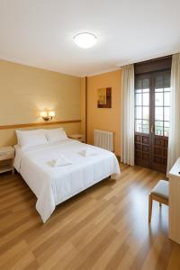 una camera da letto con un grande letto bianco e pavimenti in legno di Elara MSuites a Viveiro