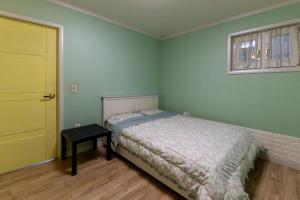 a bedroom with a bed and a table and a door at Namhae Frankfurt Pension in Namhae