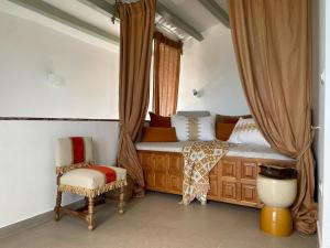 a bedroom with a bed with curtains and a chair at H&B COSTABLANCA in Villajoyosa
