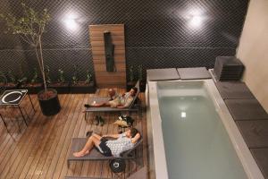 a group of people sitting on benches next to a swimming pool at Faz Hostel Boutique in Córdoba