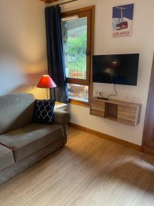 a living room with a couch and a flat screen tv at Cozy studio 3 guests, private terrace, inside pool, spa, luxurious residence, ski-in ski-out in Bourg-Saint-Maurice