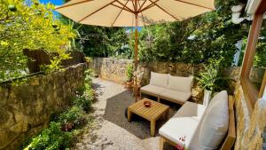 eine Terrasse mit einem Sonnenschirm, Stühlen und einem Tisch in der Unterkunft Troi Landetxea, Casa Rural Con encanto en el Goierri, Gipuzkoa, País Vasco in Mutiloa