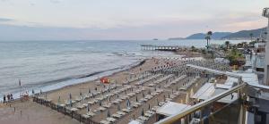 a beach with chairs and umbrellas and a pier at La Risacca in Pietra Ligure