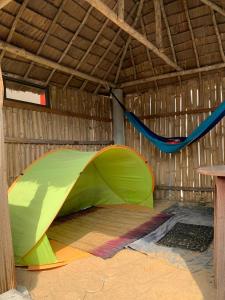 a green tent and a hammock in a building at Maison calme et fleurie in Cotonou