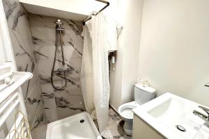 a white bathroom with a shower and a toilet at Le St Roch - Chic & Pratique in Roanne