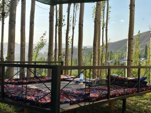 a bed in a forest with trees in the background at Shahzod Guesthouse & Homestay in Gelen