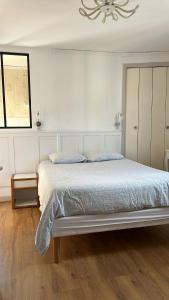 ein weißes Schlafzimmer mit einem großen Bett und einem Kronleuchter in der Unterkunft Bristol Manor N20 terrasse cuisine et chambre in Néris-les-Bains