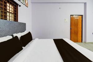 a bedroom with a white bed and a wooden door at Hotel O Green leaf inn in Surūrnagar +22 photos