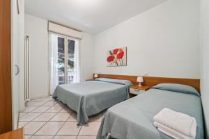 two beds in a room with a window at Green Village Accommodations in Colico