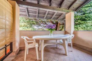 a table and chairs on a porch with a vase of flowers at Green Village Accommodations in Colico