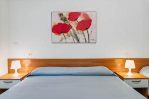 a bedroom with a bed with red flowers on the wall at Green Village Accommodations in Colico