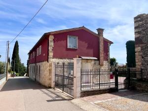 a red house with a gate in front of it at Villavecchia in Castegnero