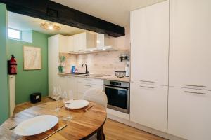 a kitchen with a wooden table and white cabinets at Suite Vieille Ville - Calme et Cosy - Parking gratuit in Sélestat