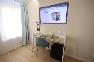a desk in a room with a monitor on the wall at Photomusic Boutique Rooms in Senigallia